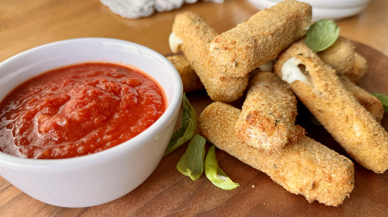 mozzarella sticks next to a bowl of tomato sauce
