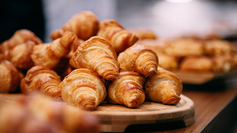 A pile of freshly baked croissants on wooden tray