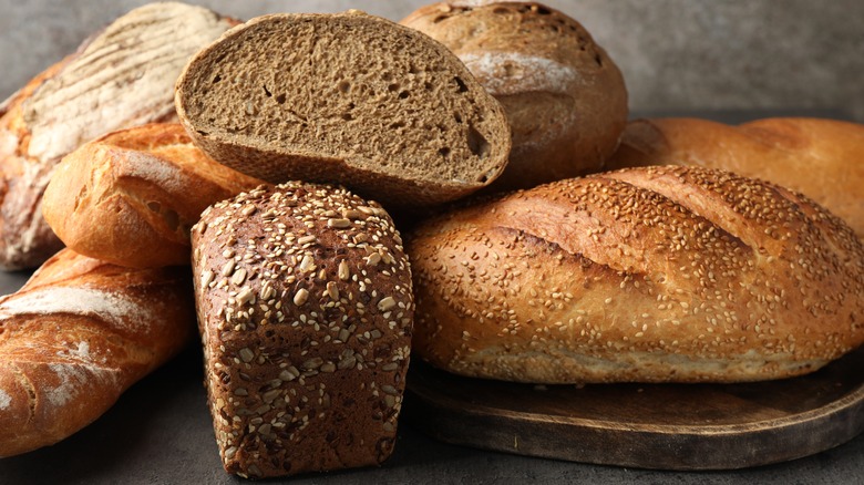 A variety of wheat, rye, and multigrain fresh baked bread in a pile on a table