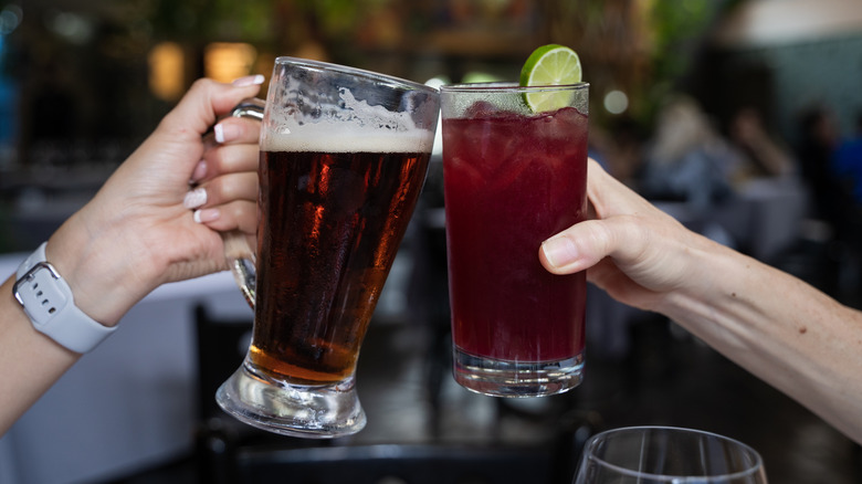 Hands clinking glasses of beer and sangria together