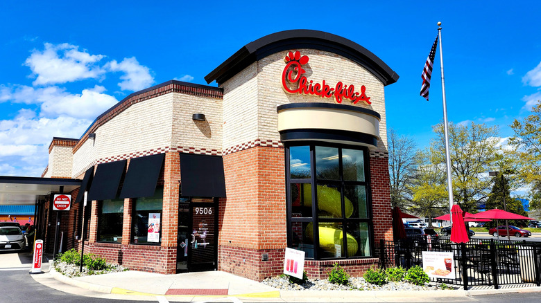 The exterior of a Chick-fil-A restaurant features outdoor tables and a drive-thru.