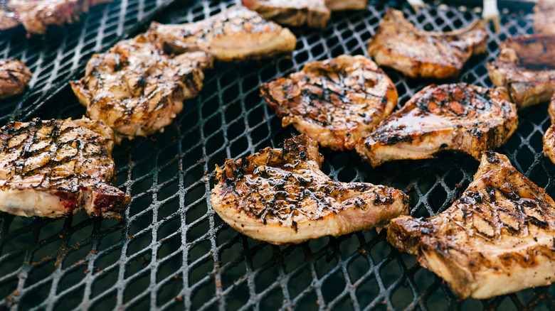 Pork chops on a charcoal grill.
