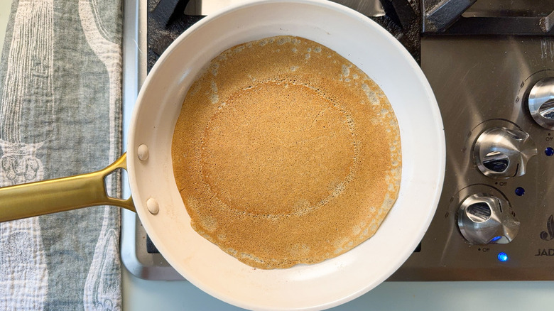Buckwheat crepe cooking in pan on stovetop