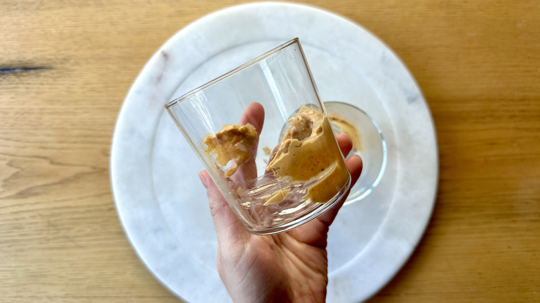 Hand holding glass smeared with peanut butter