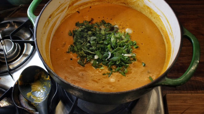 adding scallions and basil to soup