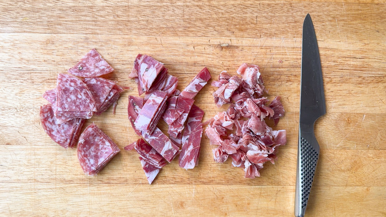 Italian cured meats in bite-sized pieces on cutting board with knife